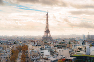 Tower and buildings in city against cloudy sky