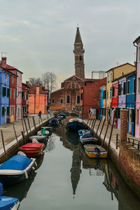 Boats moored in canal against buildings in city