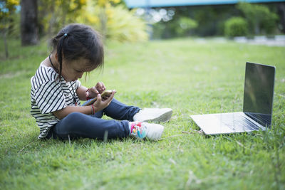 Young woman using laptop while sitting on field