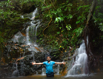 Boy standing by waterfall in forest