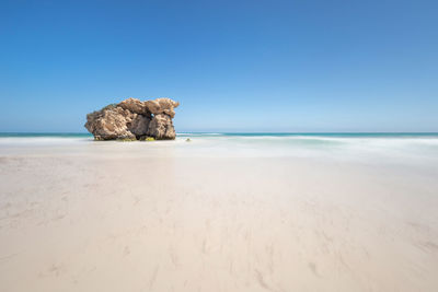 Scenic view of beach against clear blue sky
