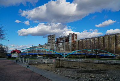 Bridge over river by buildings against blue sky