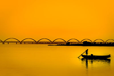 Silhouette person on boat against sky during sunset