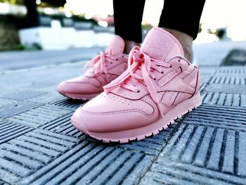 Low section of woman standing on pink shoes