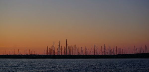 Scenic view of lake and silhouette field against sky during sunset