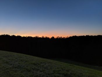 Silhouette trees on field against sky during sunset