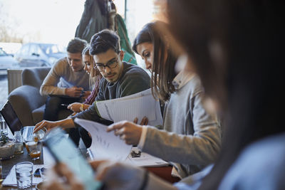 Group of friends sitting together in a cafe with laptop and documents