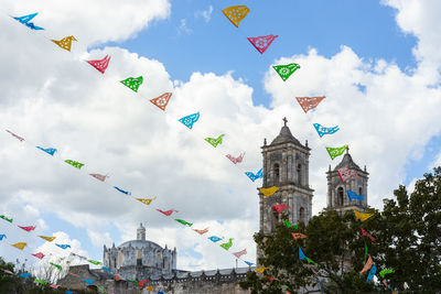 Low angle view of multi colored flags hanging against buildings in city