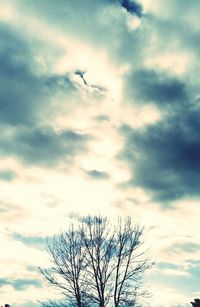 Low angle view of bare trees against cloudy sky