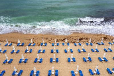 Aerial view of a fantastic beach with, blue lounge chairs, umbrellas, and turquoise sea.