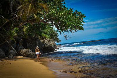 Woman walking on beach against sky