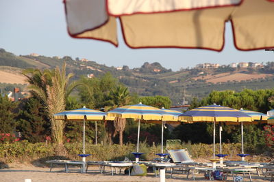 Chairs and tables by swimming pool against sky