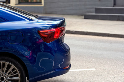 Rear half with rear lights of a parked car on the side of the street, vehicle exterior details