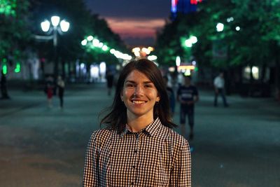 Portrait of smiling woman standing on street at night