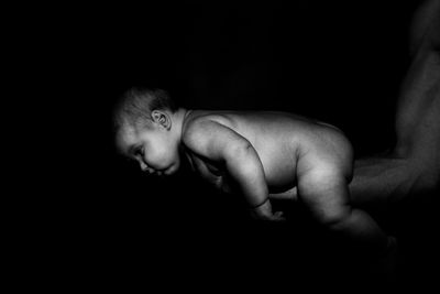 Portrait of shirtless baby boy against black background