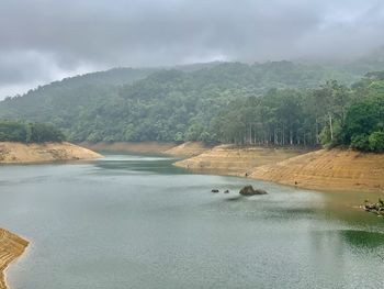 Scenic view of river by mountains against sky