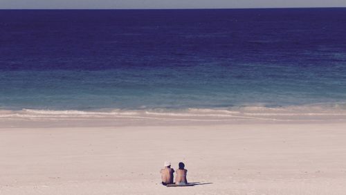 Rear view of people sitting at beach