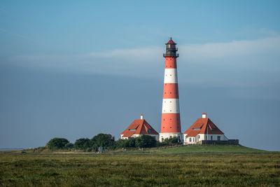 Lighthouse by sea against sky