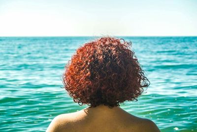 Rear view of young woman against sea