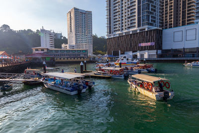 Boats in river by buildings in city