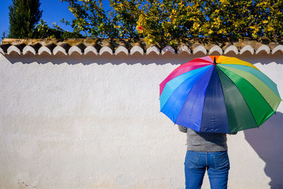 Rear view of man standing against multi colored umbrella