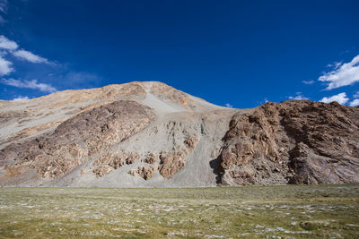 Scenic view of land and mountains against blue sky