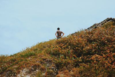 Low angle view of man standing on hill against sky