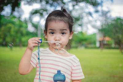 Portrait of girl blowing bubbles at park