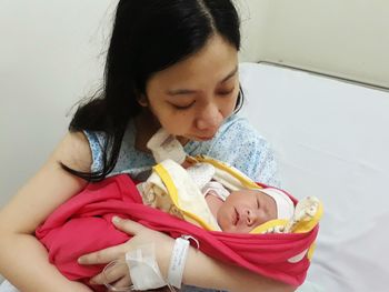 Close-up of woman holding cute baby girl on hospital bed