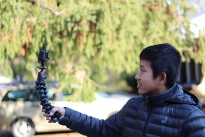 Smiling young man taking selfie while standing outdoors