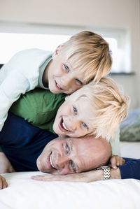 Portrait of happy sons lying on father