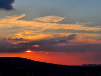 Silhouette landscape against dramatic sky during sunset