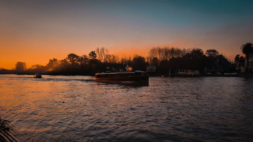 Silhouette trees by sea against sky during sunset