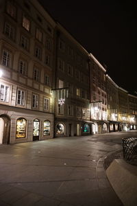 Illuminated street in front of building at night