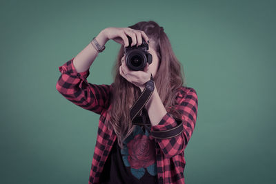 Midsection of woman photographing against gray background
