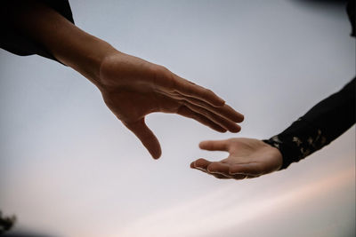 Close-up of hands against sky