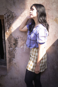 Full length of woman standing against wall