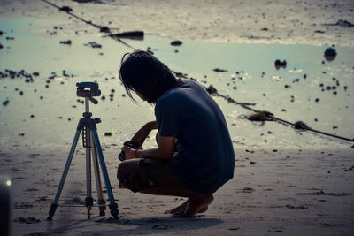 Rear view of man photographing at beach