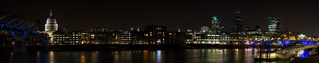 Illuminated modern buildings in city against sky at night