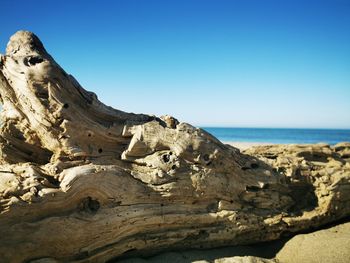 Rock formations in sea against clear blue sky