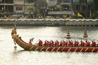 People on boat in river against buildings