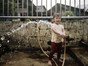 Full length portrait of girl playing with garden hose