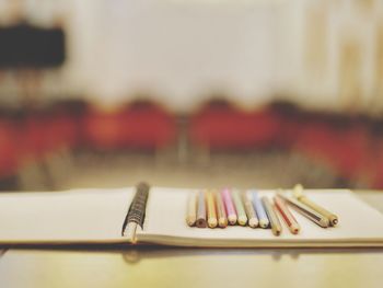 Close-up of colored pencils with book on table