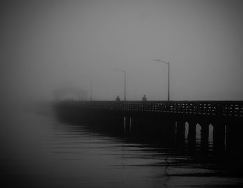 Pier over lake against sky during foggy weather