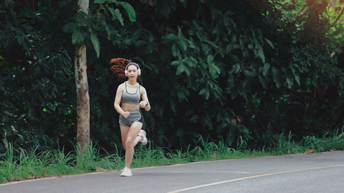 Full length of young woman running on road