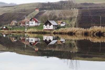 Houses by lake and buildings against mountain