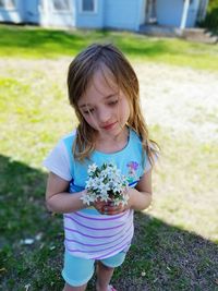 Girl holding flowers while standing on field