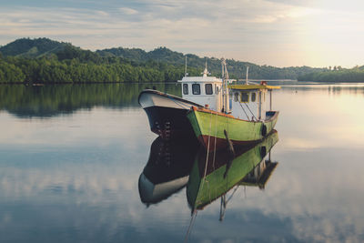 Boat moored on lake against sky