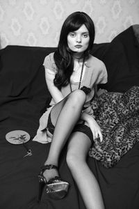 Portrait of young woman sitting on bed at home