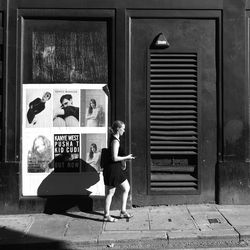 Full length of man on footpath by window